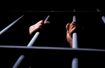 Inmate Grabbing Cell Bars --- Image by © Ken Glaser/Corbis