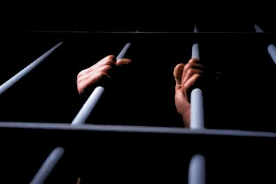 Inmate Grabbing Cell Bars --- Image by © Ken Glaser/Corbis